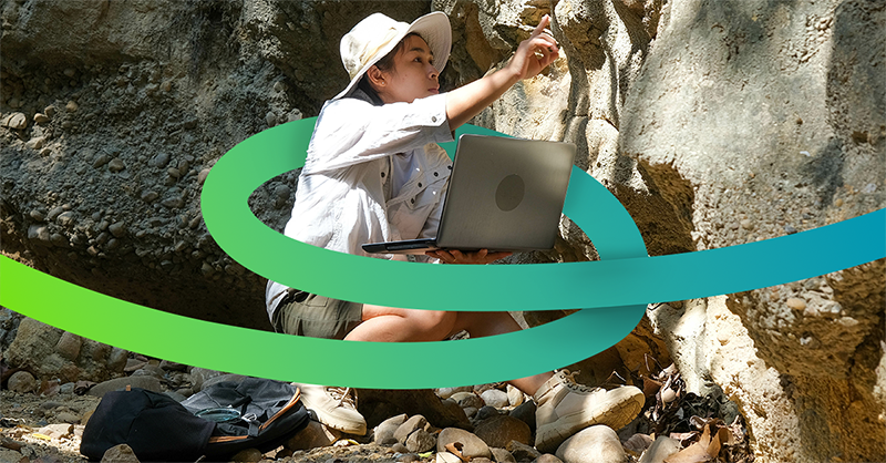An archeologist logging fossils on a laptop in the field surrounded by a loop of color