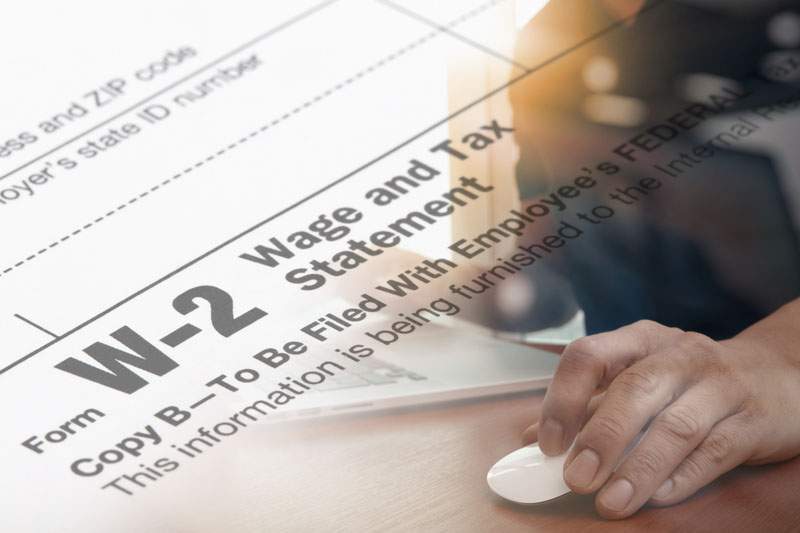 Persona frente a una computadora con un formulario de impuestos W-2