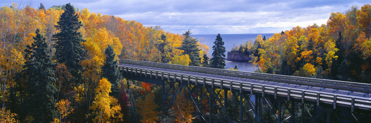 Puente con vista panorámica a un lago rodeado de árboles en otoño